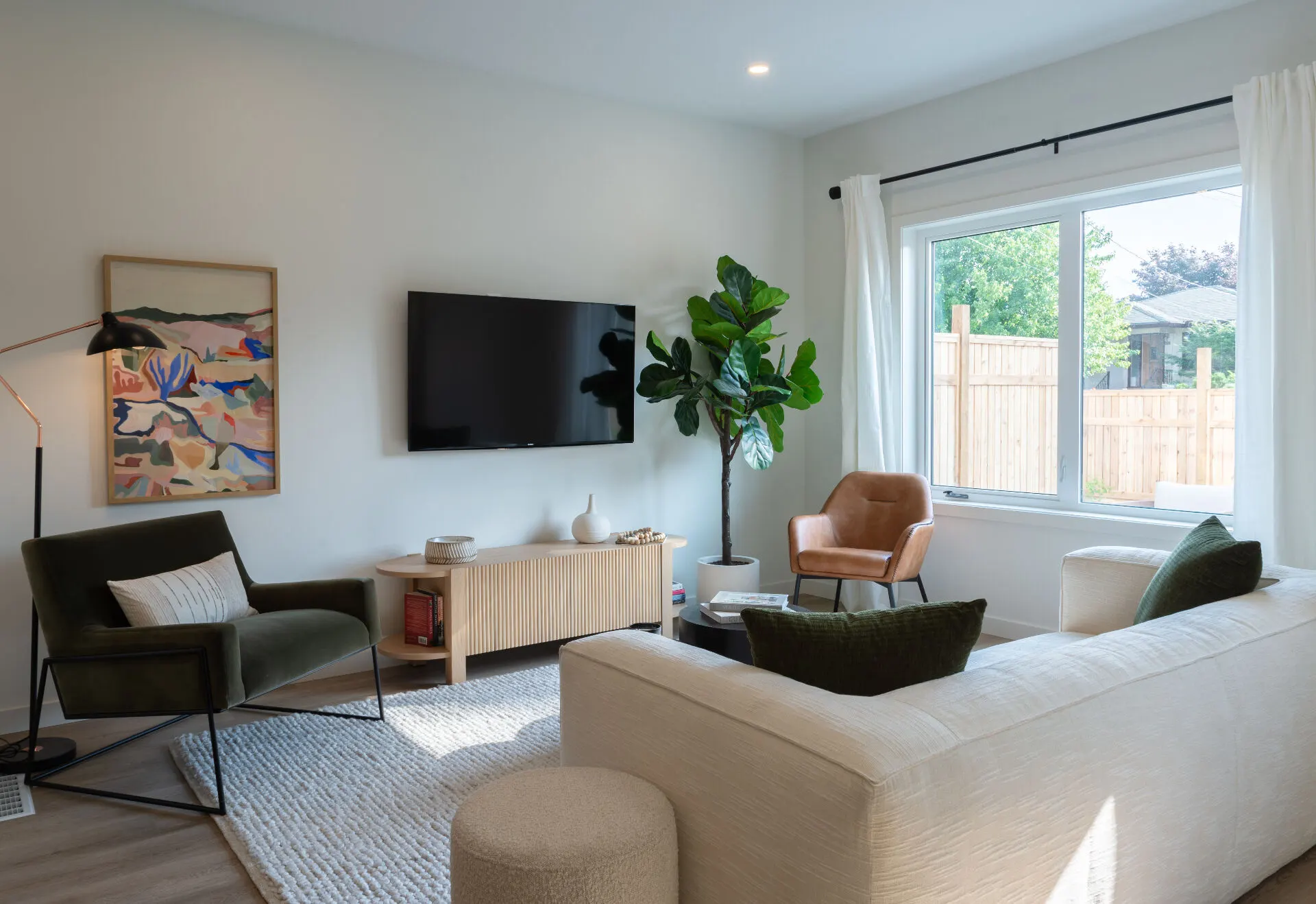 Urban Collection living room interior in Penticton, BC: linen sectional, fiddle-leaf fig, and abstract wall art in a sunlit space