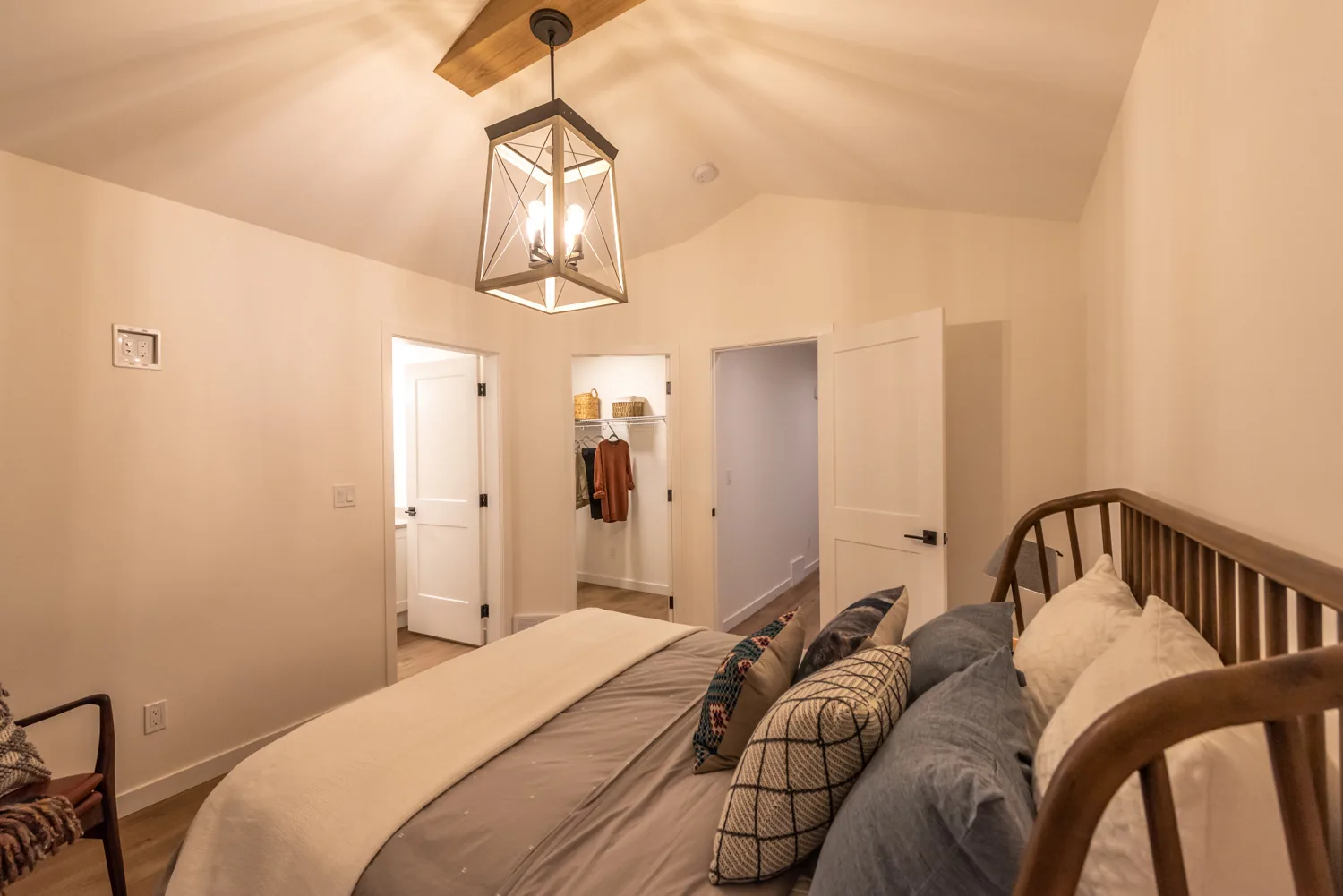 Hastings Ave bedroom, Penticton BC: vaulted ceiling with wood beam, lantern pendant light, spindle bed frame, and a walk-in closet