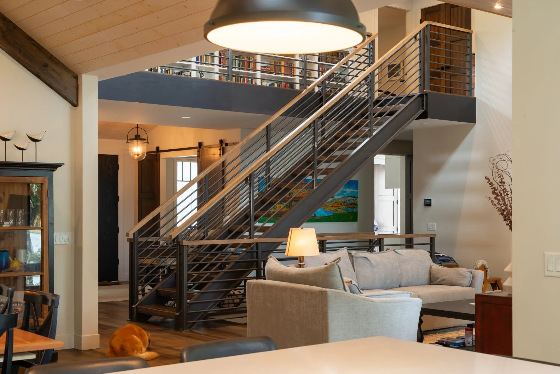 Sundial living room in Oliver, BC: open staircase, loft library and warm timber ceiling