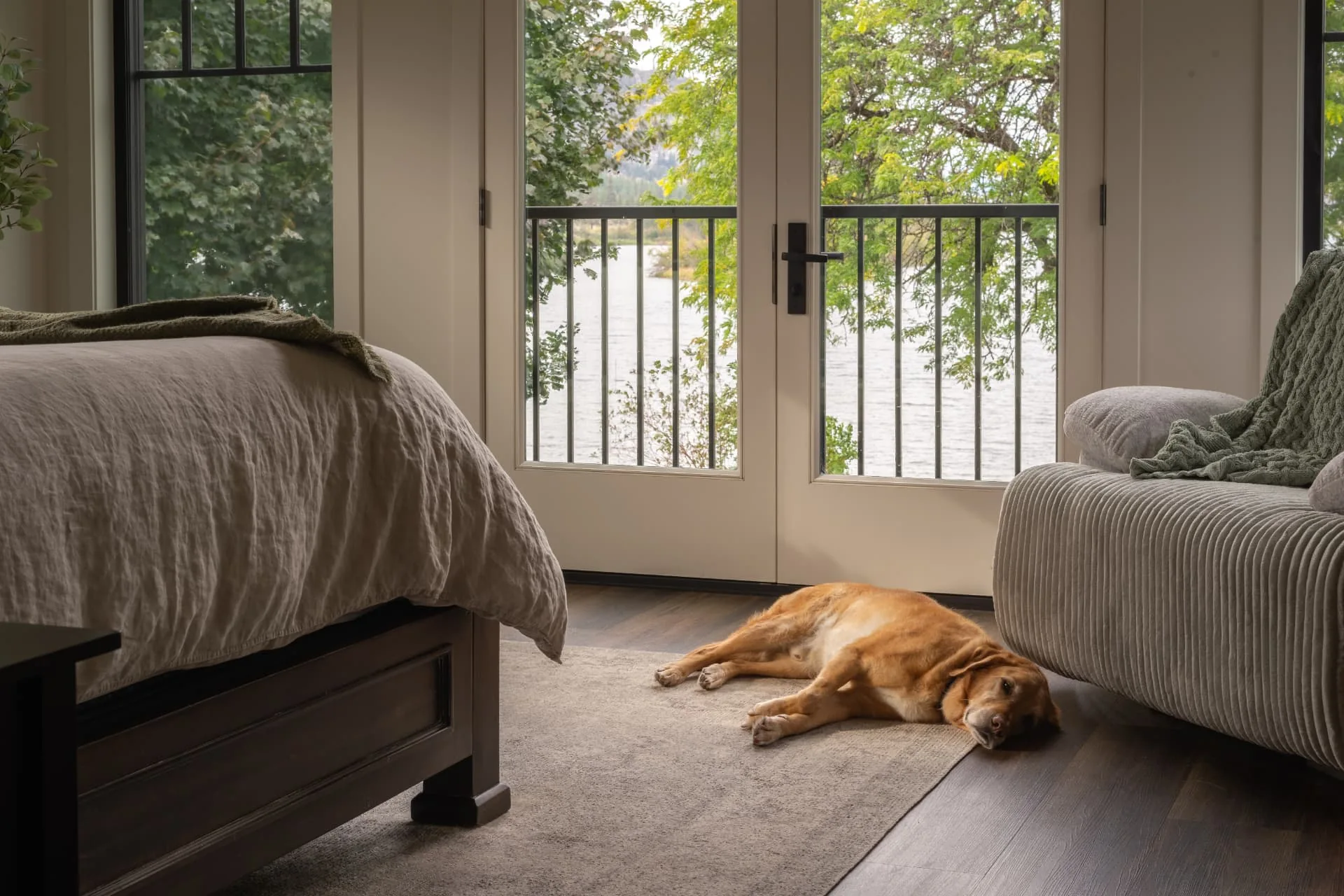 Sundial bedroom in Oliver, BC: lake view through glass doors and a dog resting beside the bed