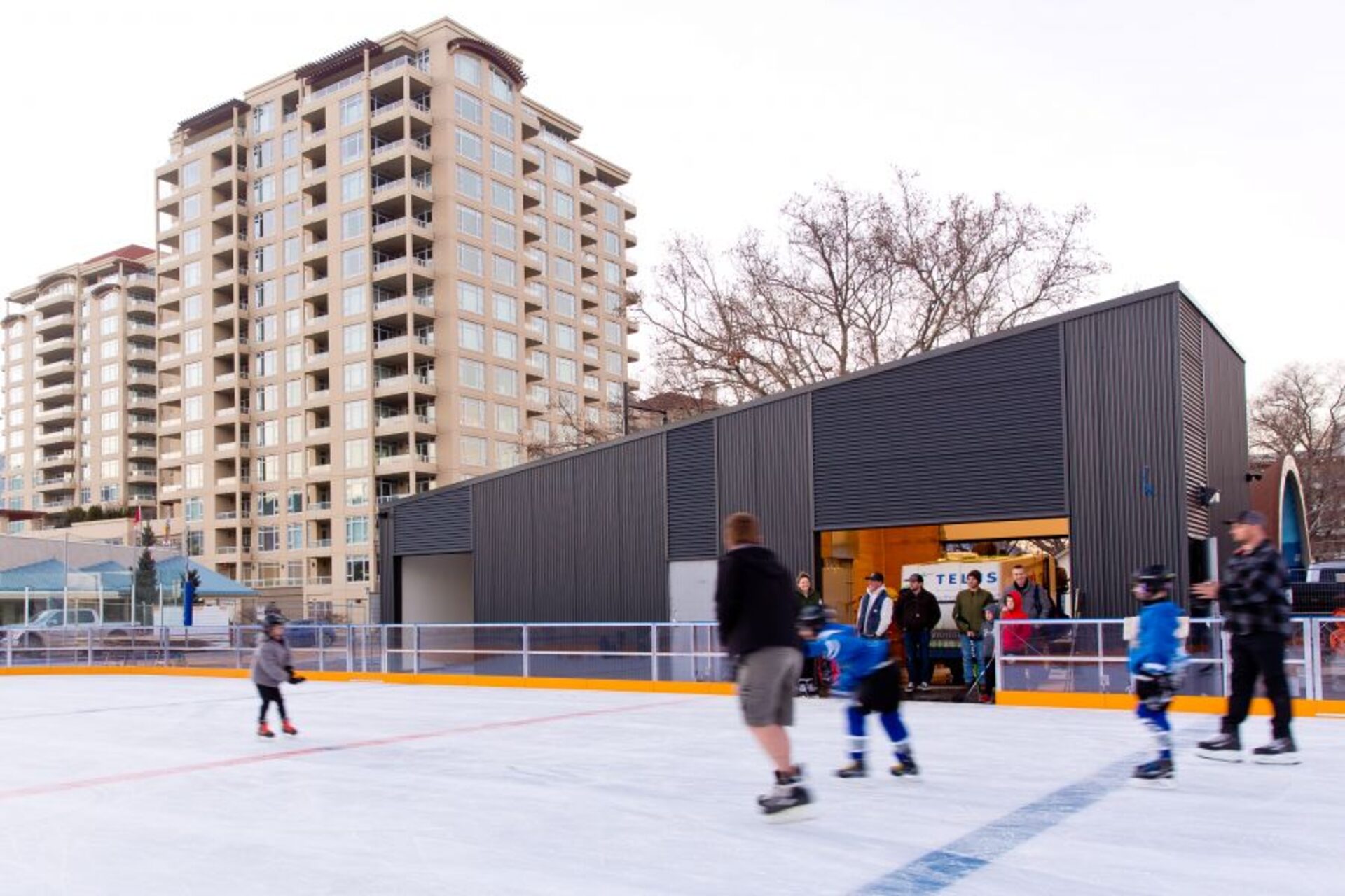 Families and kids skating at the Activate Penticton Society outdoor rink downtown, with the SS Sicamous tower in the background