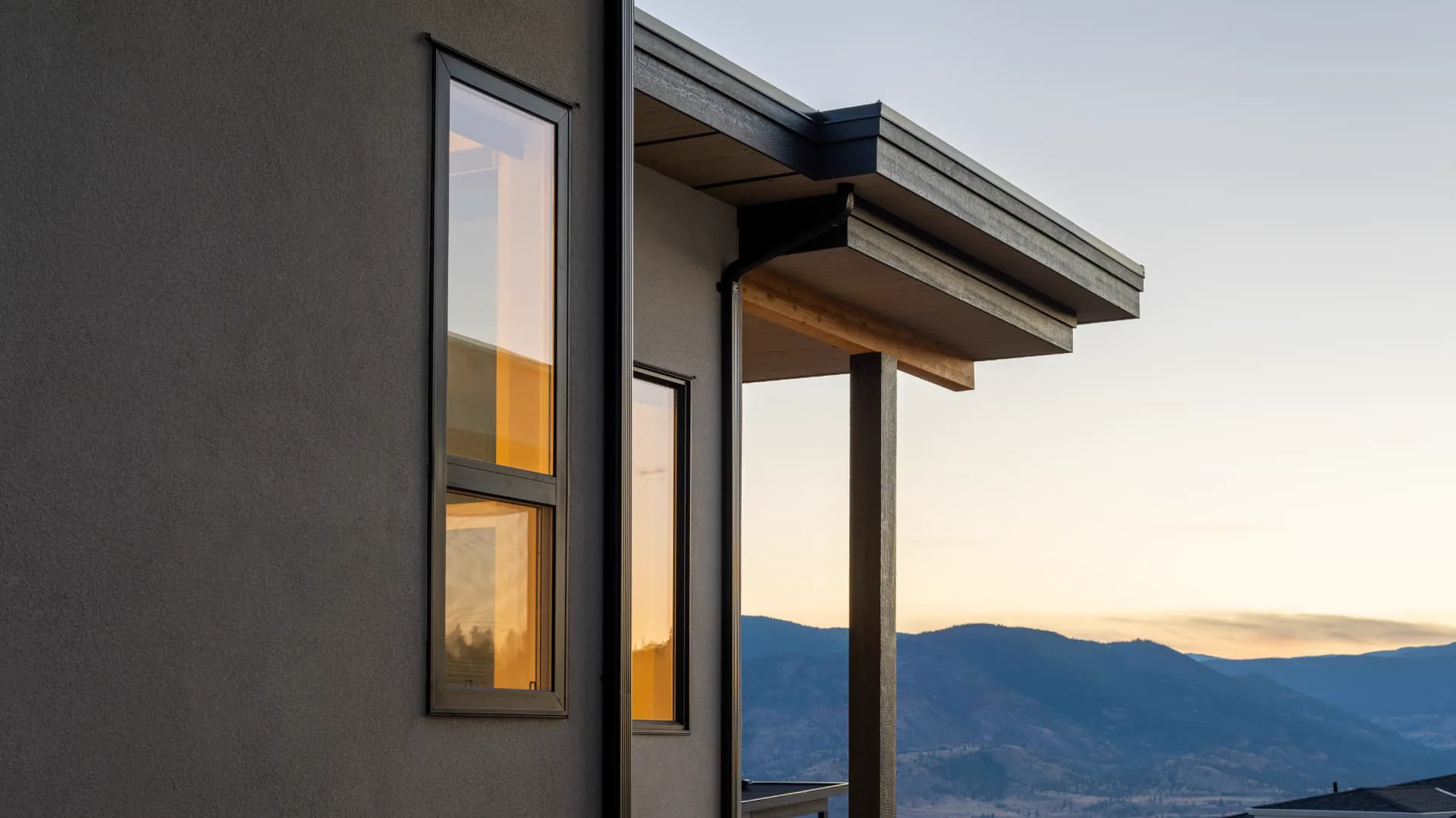 Fawn Court exterior detail, Penticton BC: contemporary dark facade and roofline framing an Okanagan mountain view at sunset