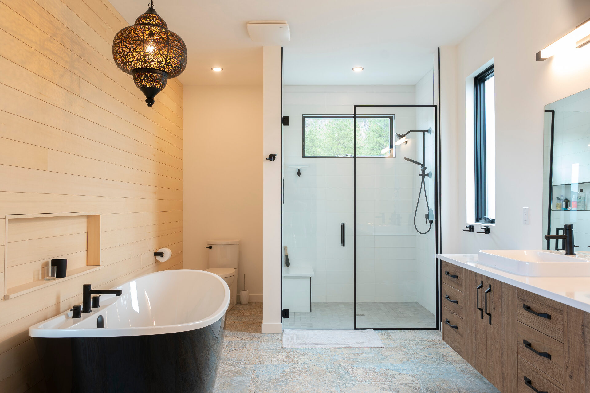 Primary bathroom with freestanding black soaker tub, pale shiplap wall, walk-in glass shower, and floating oak vanity.