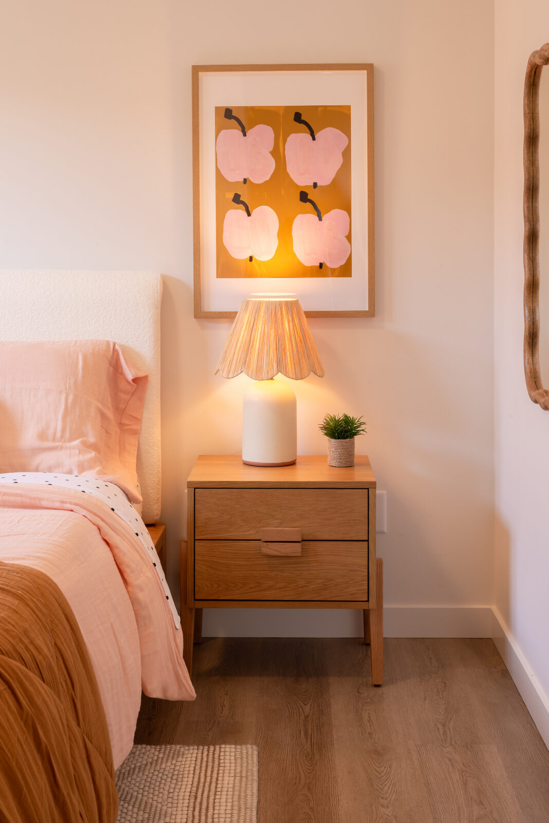 Urban Collection bedroom detail: oak nightstand with scalloped lamp, framed art, and linen bedding in a Penticton home